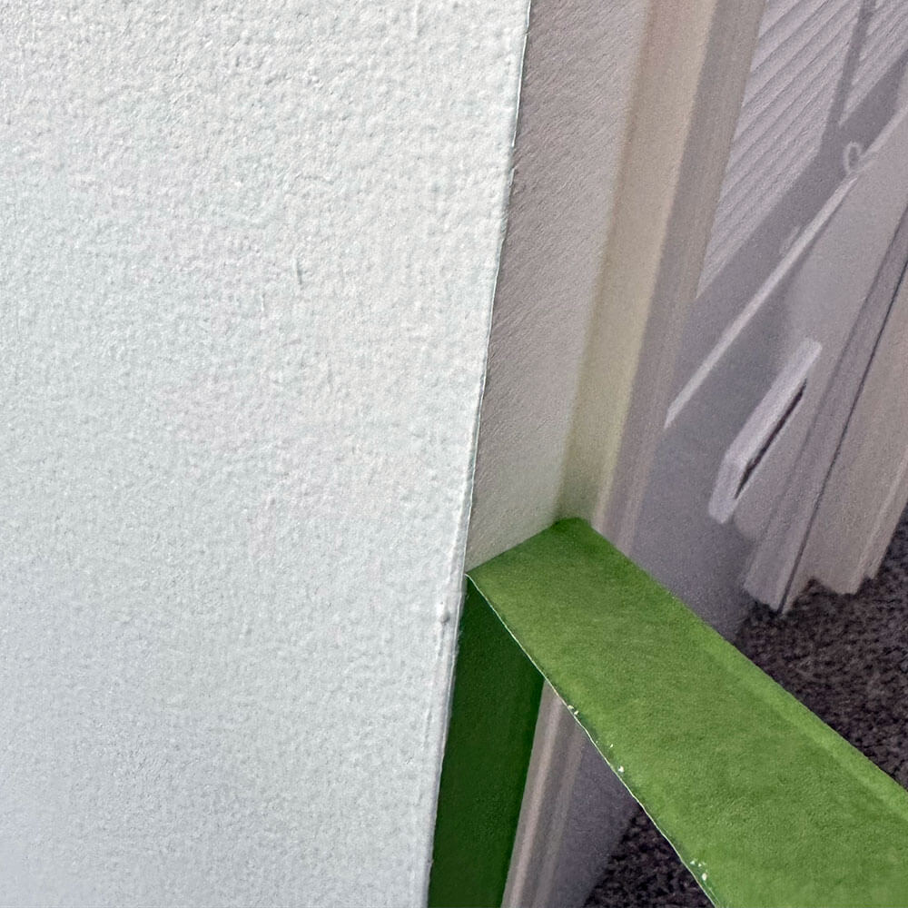 Removing painter's tape at a 45 degree angle from the edge of the freshly painted wall