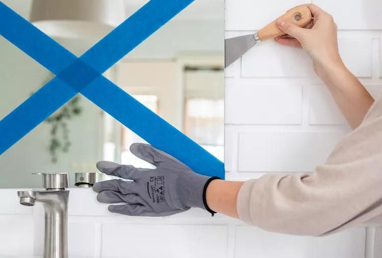 using a putty knife to separate the mirror from the wall